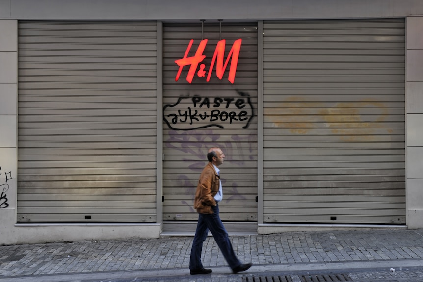 Man passes by closed shop in Athens