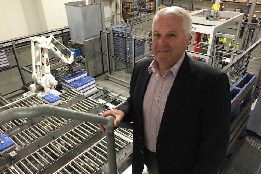 A man in a suit stands above a production line.