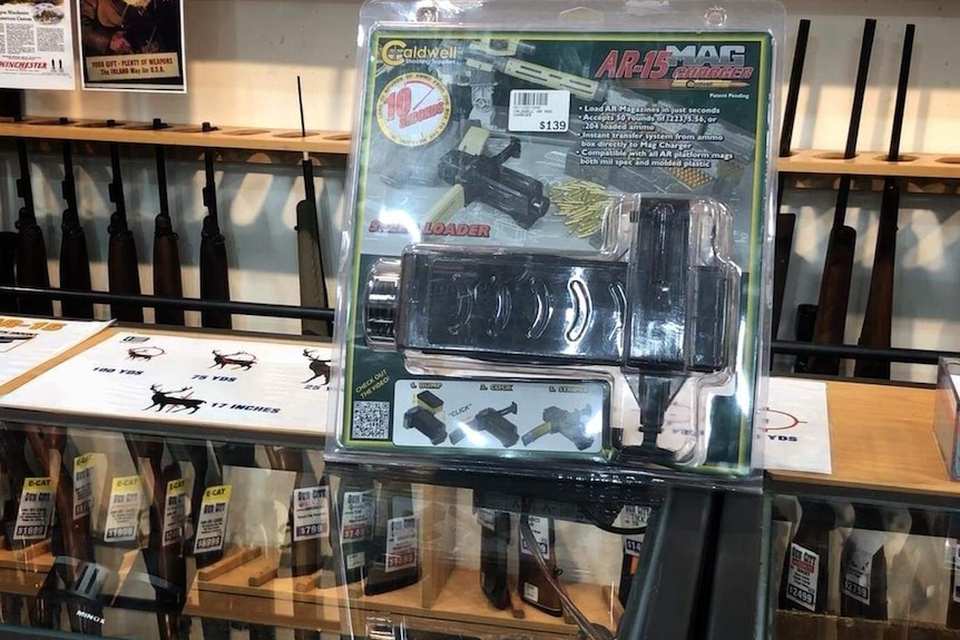 A number of firearms under a glass counter in gun shop.