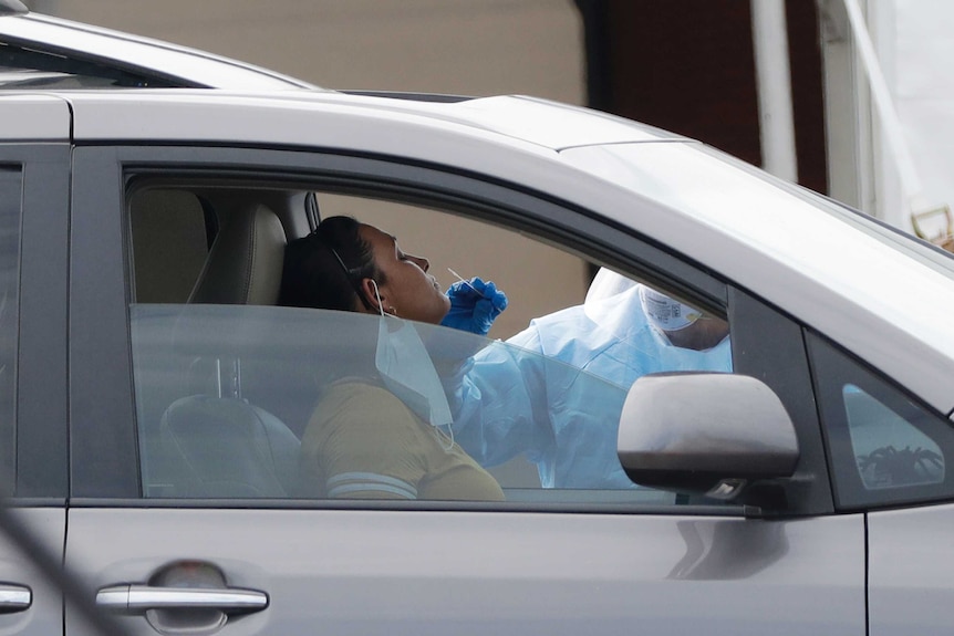 A woman sitting in a car prepares to get a coronavirus swab test.