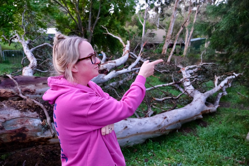 A woman next to a fallen tree.