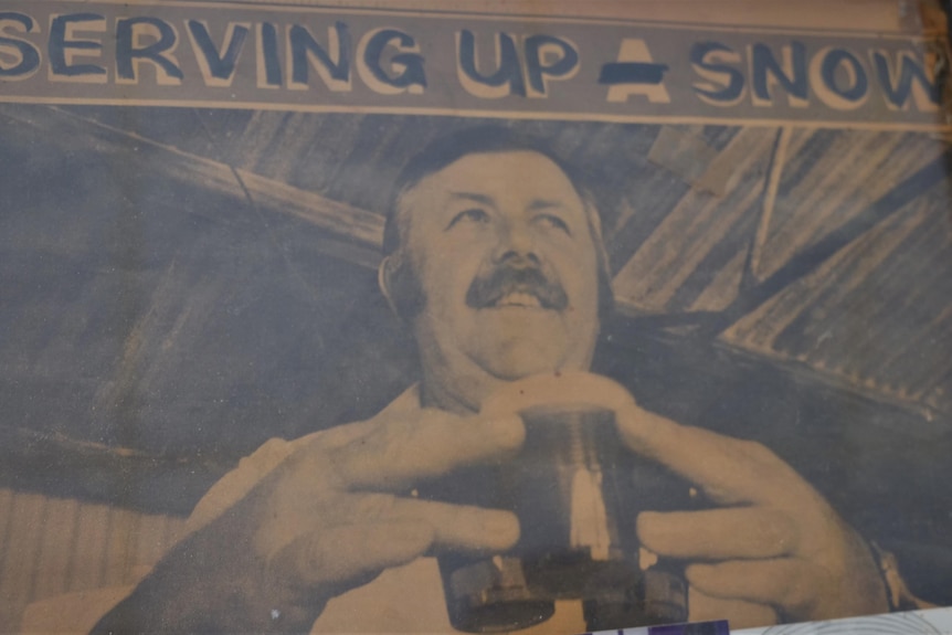 An old back and white photo of man holding onto three drinks with the caption 'serving up snow' 