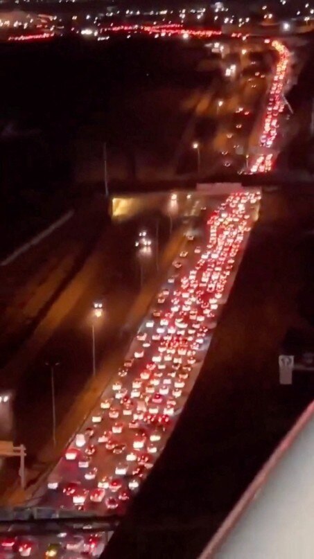 A large number of cars in a traffic jam on a highway at night, seen from above.