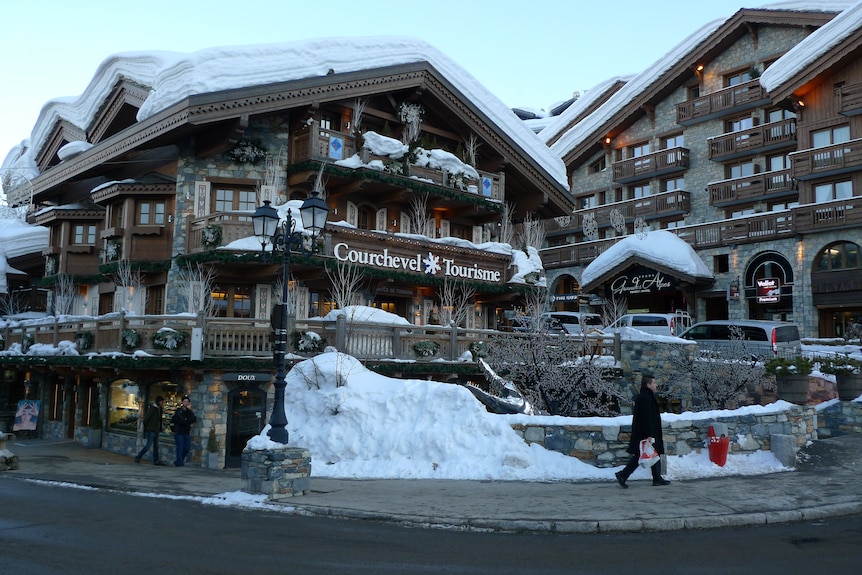 雪堆积在滑雪小屋的屋顶和阳台上。 标有高雪维尔旅游局在外面的标志