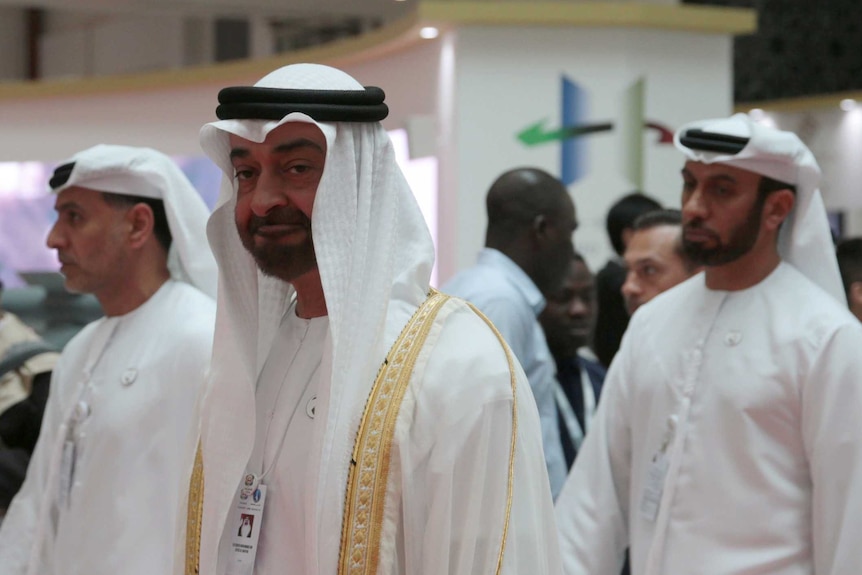 Four men wearing white traditional outfit walking, including Abu Dhabi's crown prince Mohammed bin Zayed looking at the camera.