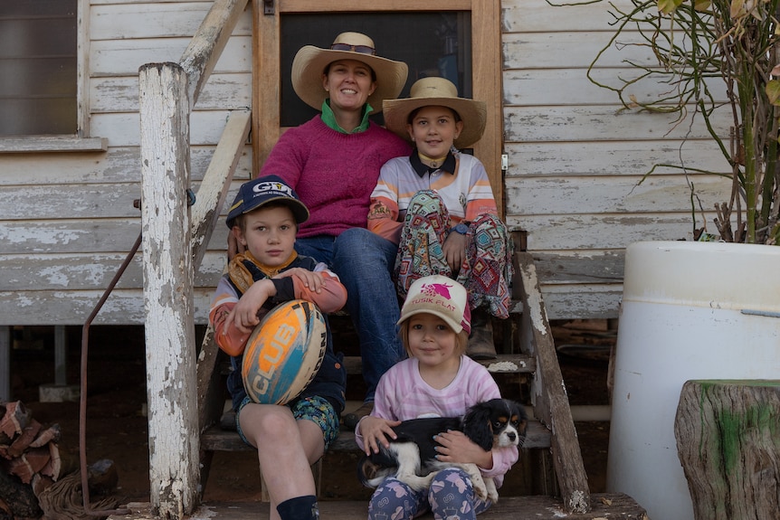 Jodie Muntelwit sits with her three children on the steps of her house.