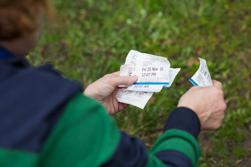 Parking tickets in a woman's hand