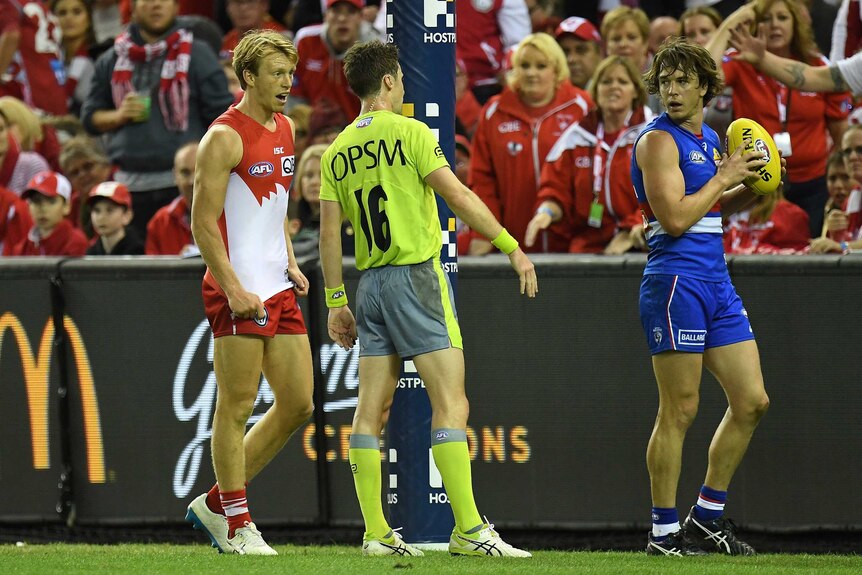 Sydney's Callum Mills (L) speaks to umpire after the Bulldogs' Liam Picken (R) gets a free kick.