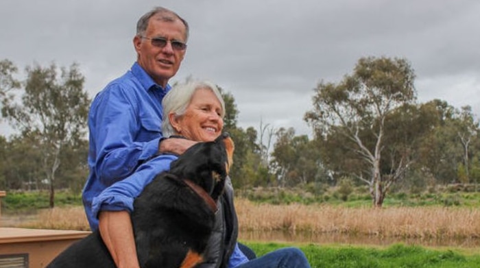 Organic farmers Kim and Wendy Muffett sitting on steps with their dog Sally.