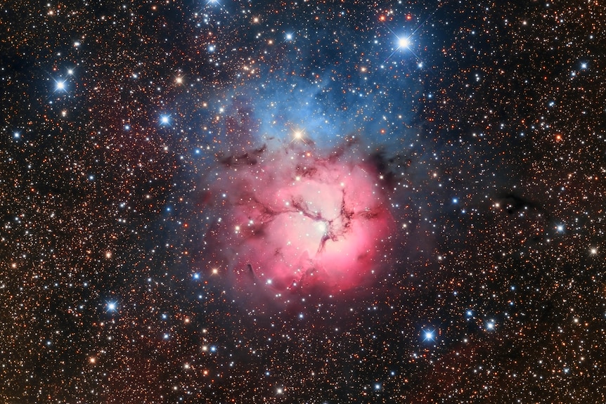 stars in a night sky with a pink hue in the centre