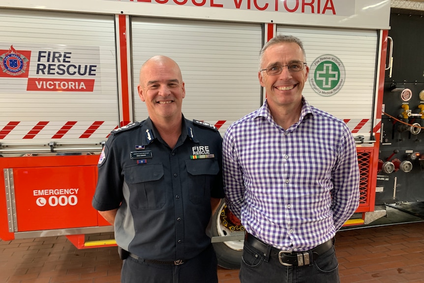 Two men standing in front of a fire truck