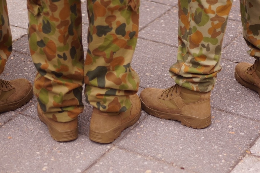 Close up of the feet of three army cadets in camouflage uniforms and boots.