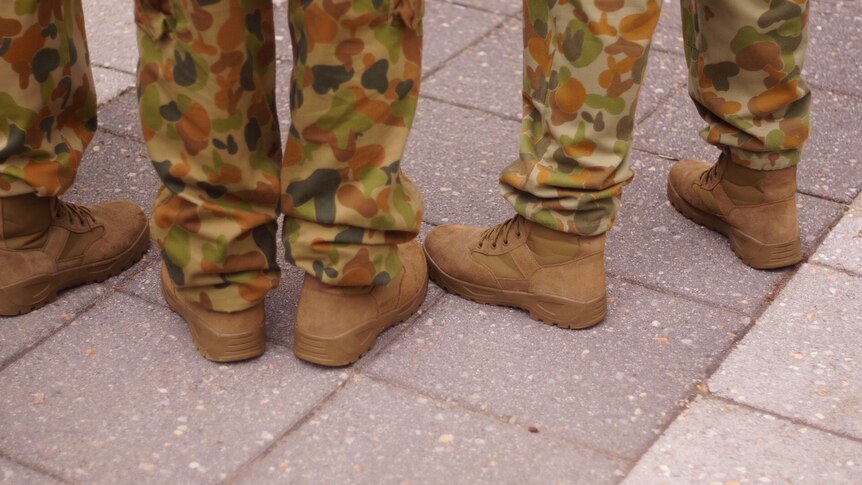 Close up of the feet of three army cadets in camouflage uniforms and boots.
