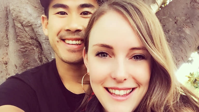 A young couple smile happily at the camera.