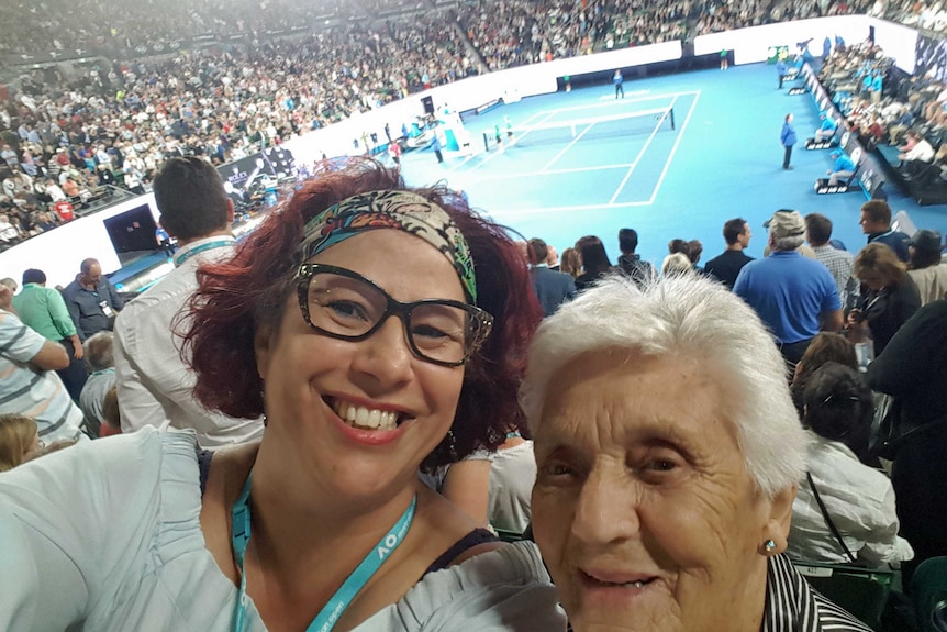 Two women at watch a tennis game.