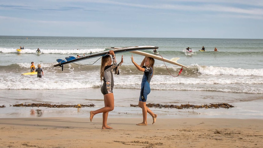 Two girls give each other a high five at the beach in Warrnambool