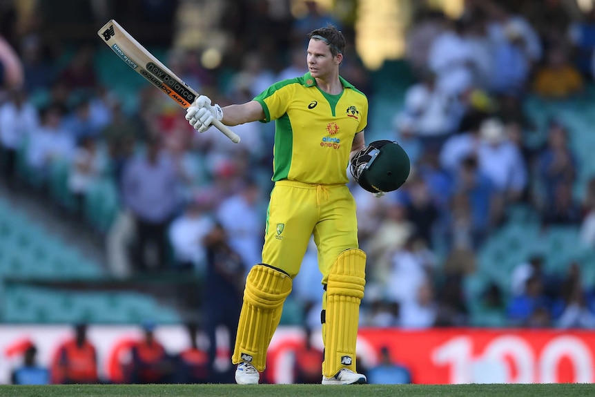 An Australian male batter points his bat to his right after scoring a century against India in Sydney.