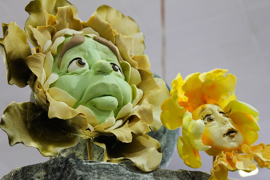 Two sugar sculptures of the flowers with faces from Alice in Wonderland.