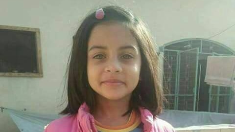 A young girl wearing a pink jacket and colourful shirt