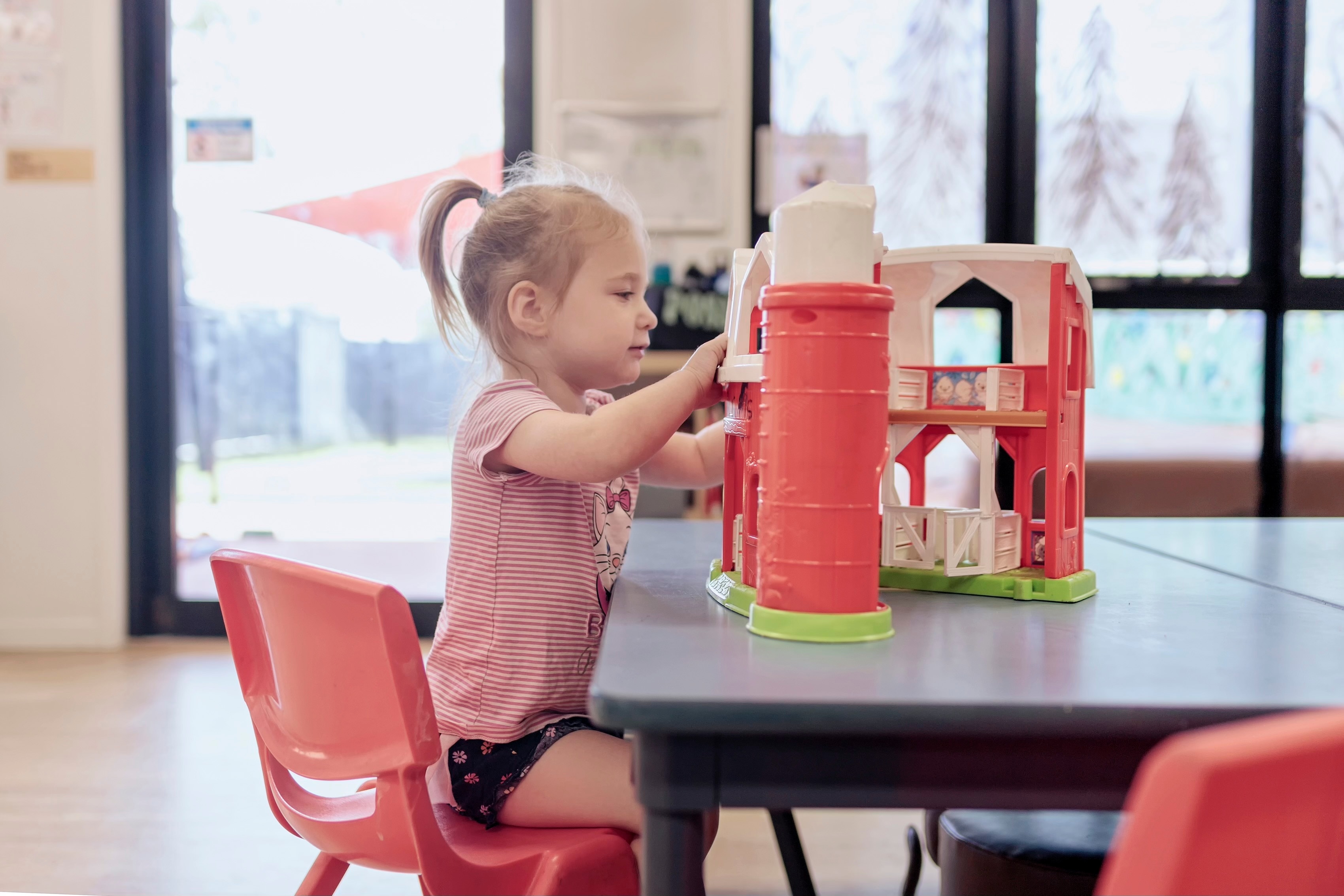 A young girl sits at a table playing with toys.