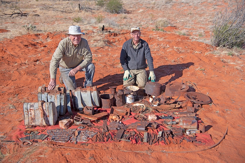 Two men crouching down in desert sitting with equipment from early explorer