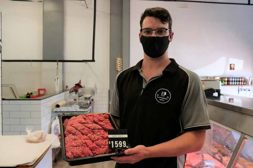 A butcher holds a tray of mince
