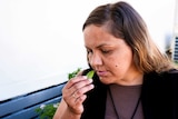 A woman smelling a chocolate mint leaf sitting down.