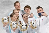 Members of the ROC figure skating team pose for selfies during the flower ceremony at Beijing Winter Olympics.