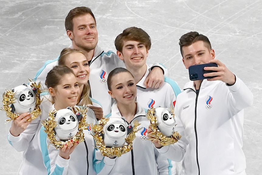 Members of the ROC figure skating team pose for selfies during the flower ceremony at Beijing Winter Olympics.