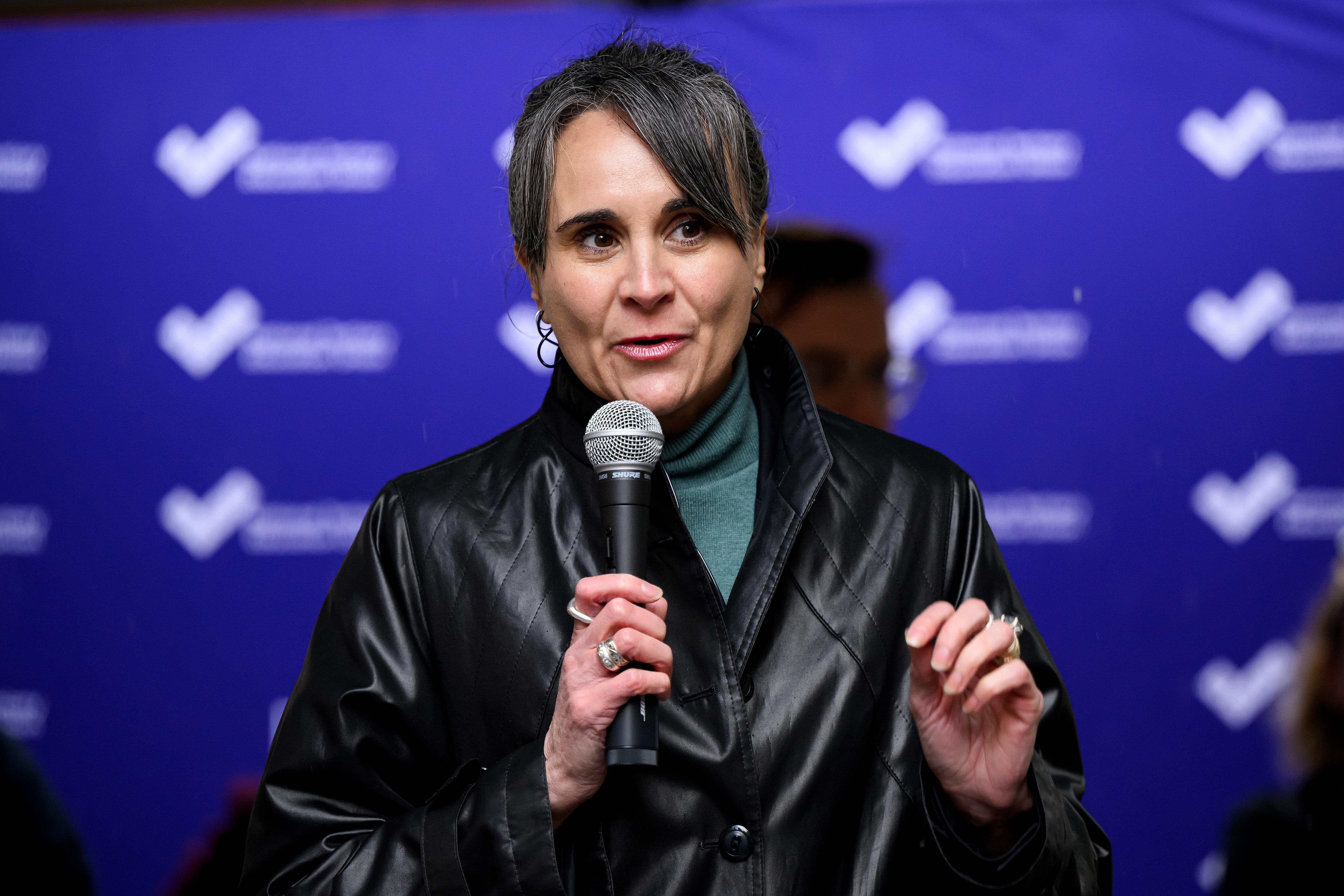 Allí está una mujer con un micrófono y habla.