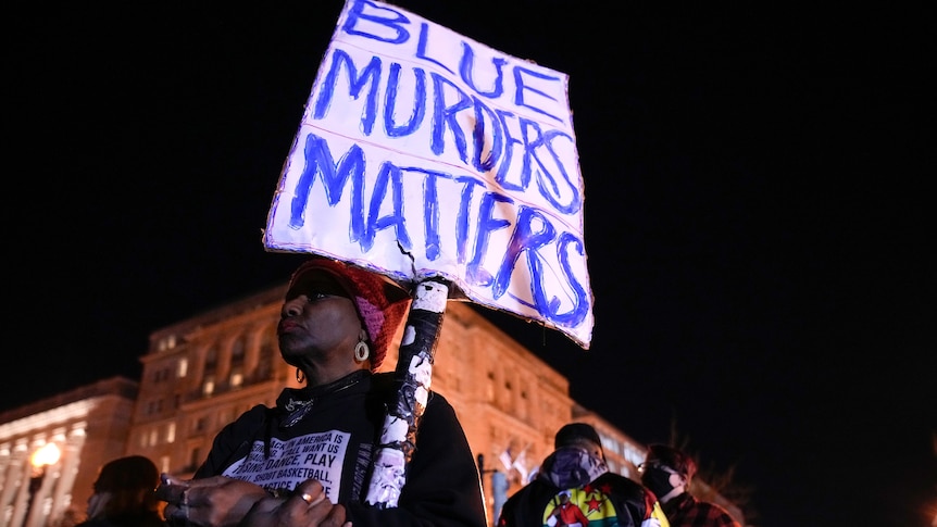 A woman demonstrates holding a sign that says "Blue Murders Matters" in Lafayette Park outside the White House.