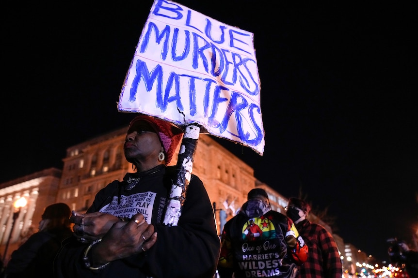 A woman demonstrates holding a sign that says "Blue Murders Matters" in Lafayette Park outside the White House.