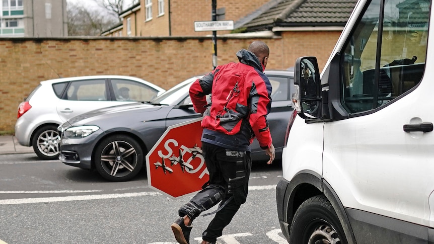 A man running away with a stop sign in his hand