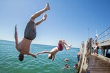 Two young men backflip of a pier