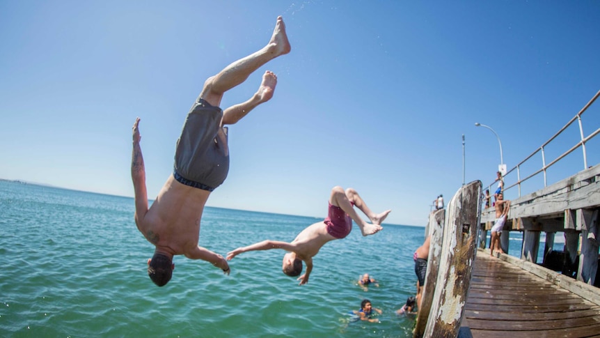 Two young men backflip of a pier