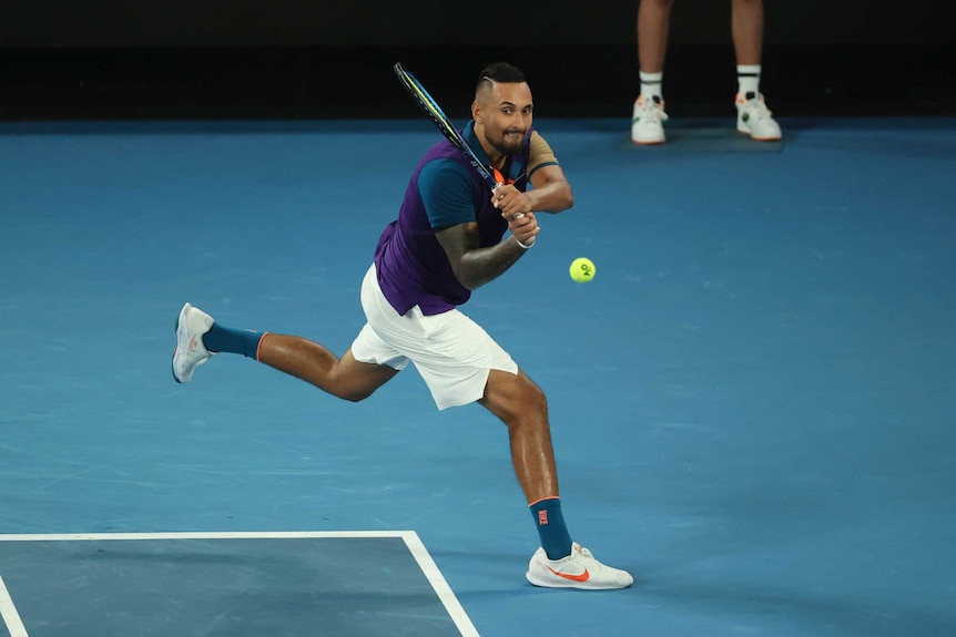 Nick Kyrgios grimaces as he hits a double-handed backhand