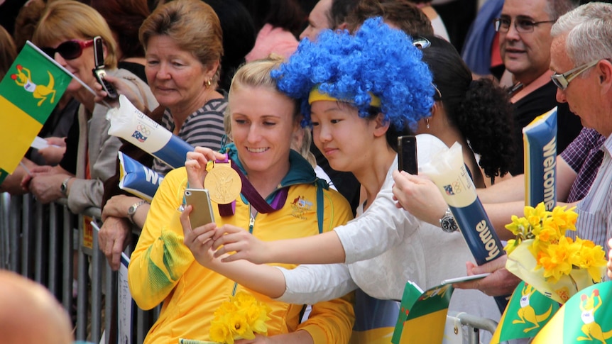 Sally Pearson stops for photos during the Welcome Home parade for Olympians in Brisbane.