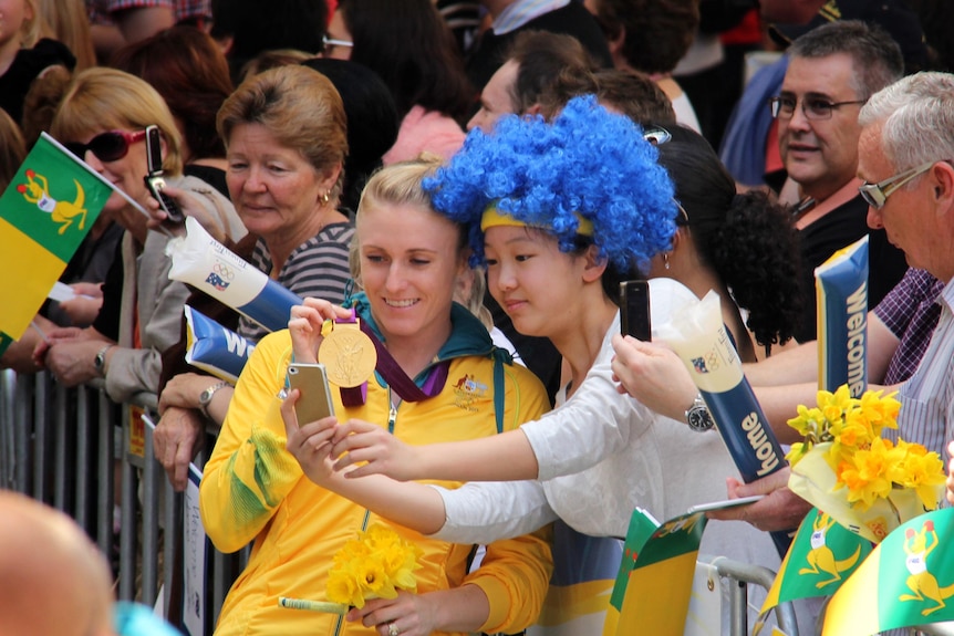 Sally Pearson stops for photos during the Welcome Home parade for Olympians in Brisbane.