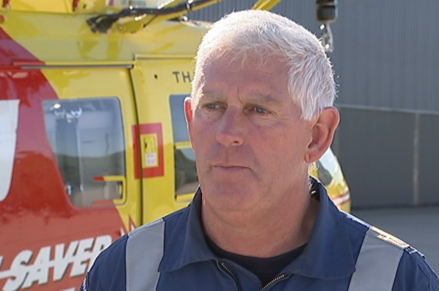 Westpac Helicopter Chief Aircrewman John Costin stands in front of a lifesaver helicopter.