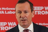 A head and shoulders shot of WA Premier Mark McGowan speaking at a media conference in front of a red Labor display.