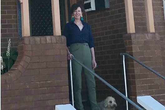 Woman standing on verandah of red brick home in country New South Wales