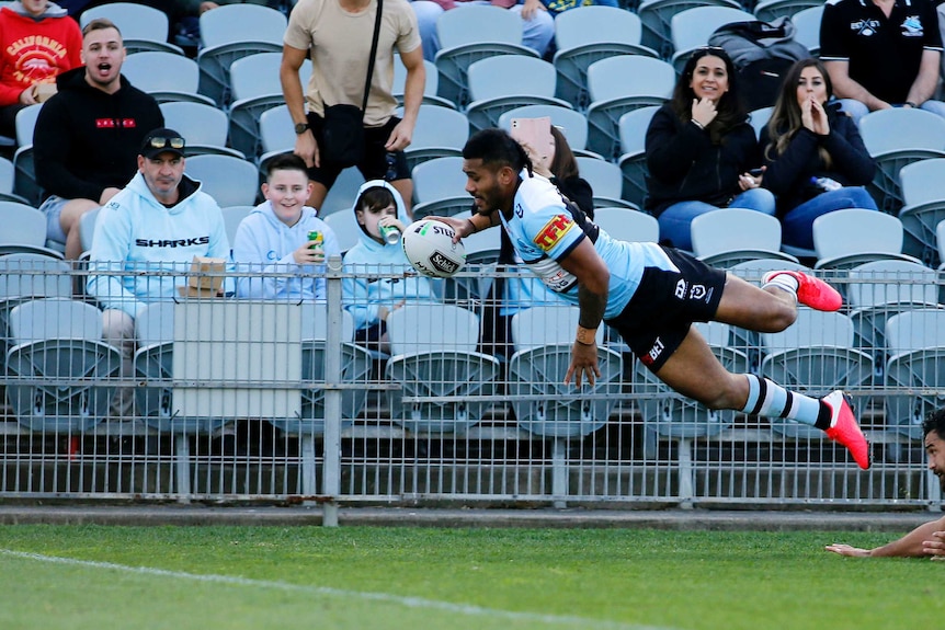 An NRL player gets airborne as he flies over the goal line to score a try.