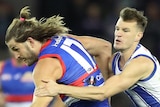 A Western Bulldogs AFL player is tackled by a North Melbourne opponent around his arms.