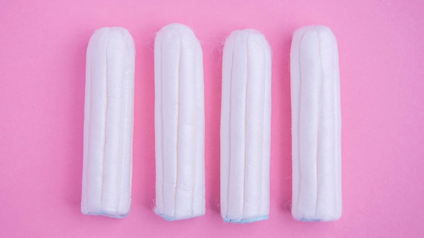Four tampons on a pink background.