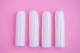 Four tampons on a pink background.