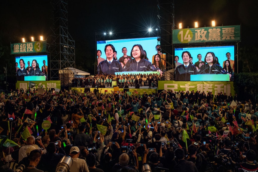 a stage surrounded by large screens show Tsai Ing-wen delivering a speech at a podium