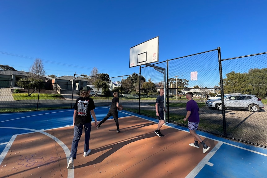 a group of four teens play basketball