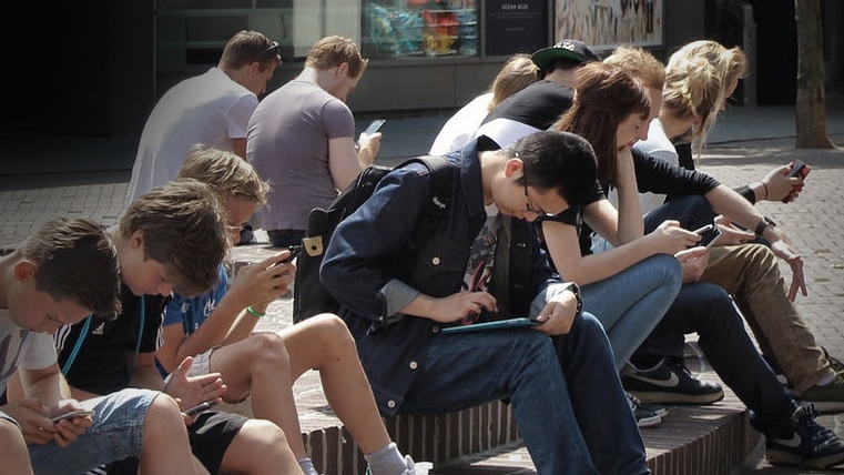 Young people in a group using mobile devices.