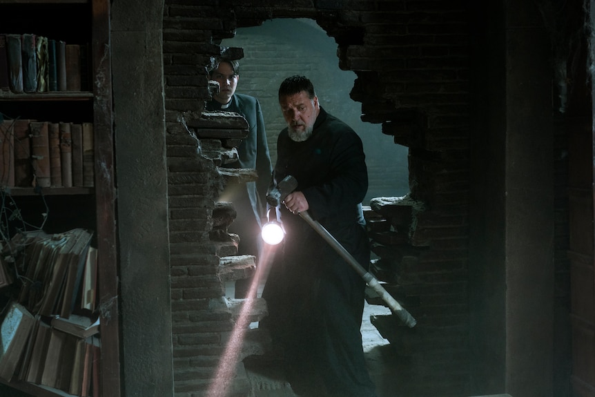 Russell Crowe in a scene from a film holding a sledge hammer.