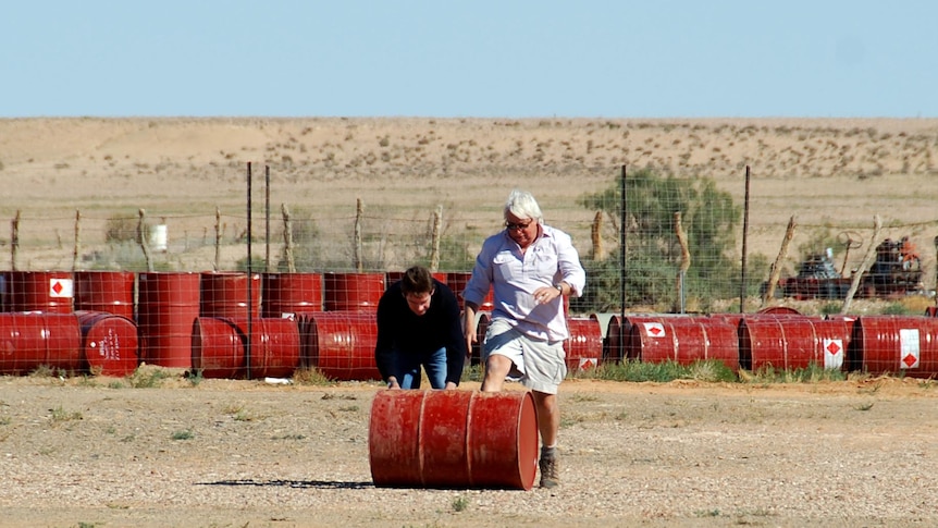 Paul Lockyer and Gary Ticehurst roll a barrel of jet fuel to the ABC helicopter